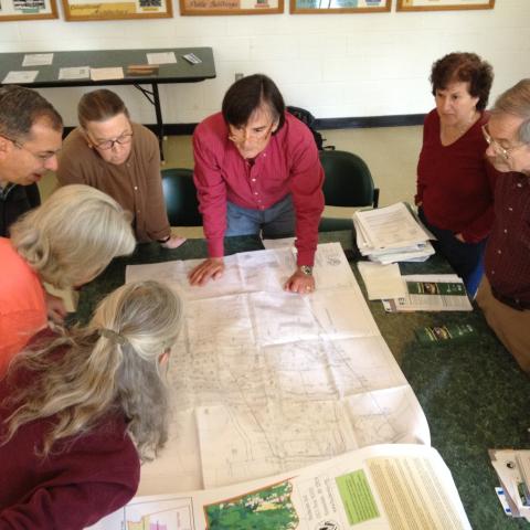 Municipal officials and volunteers gather around maps in town hall