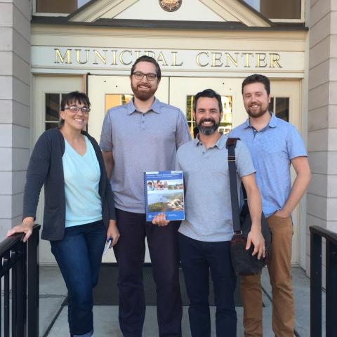 Four communitiy volunteers stand in front of Beacon city hall, and one holds a copy of our NRI Guidebook. By L Heady